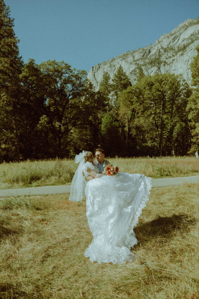 groom holding bride in his arms in yosemite national park 
