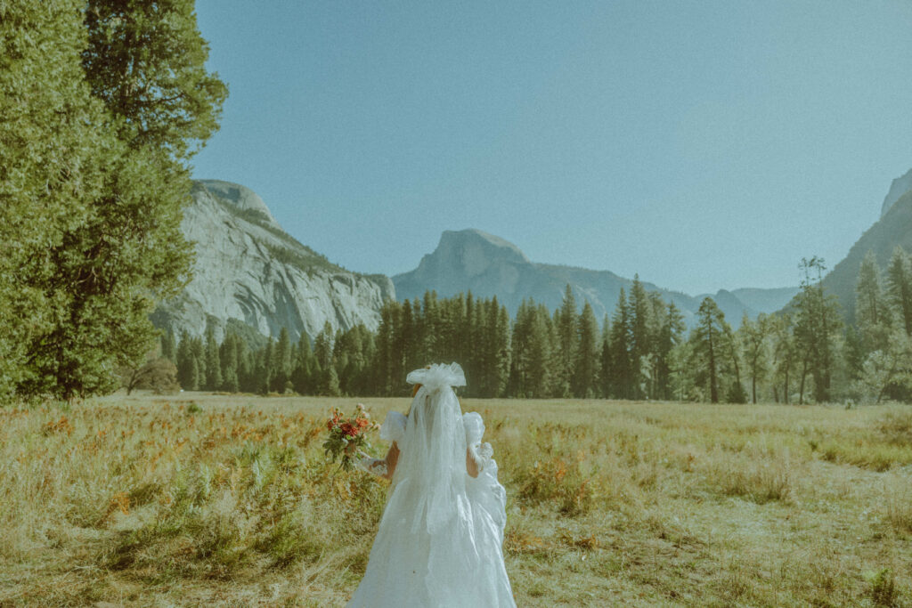 bride walking away towards half dome in vintage thrifted wedding dress in yosemite national park for her destination elopement 