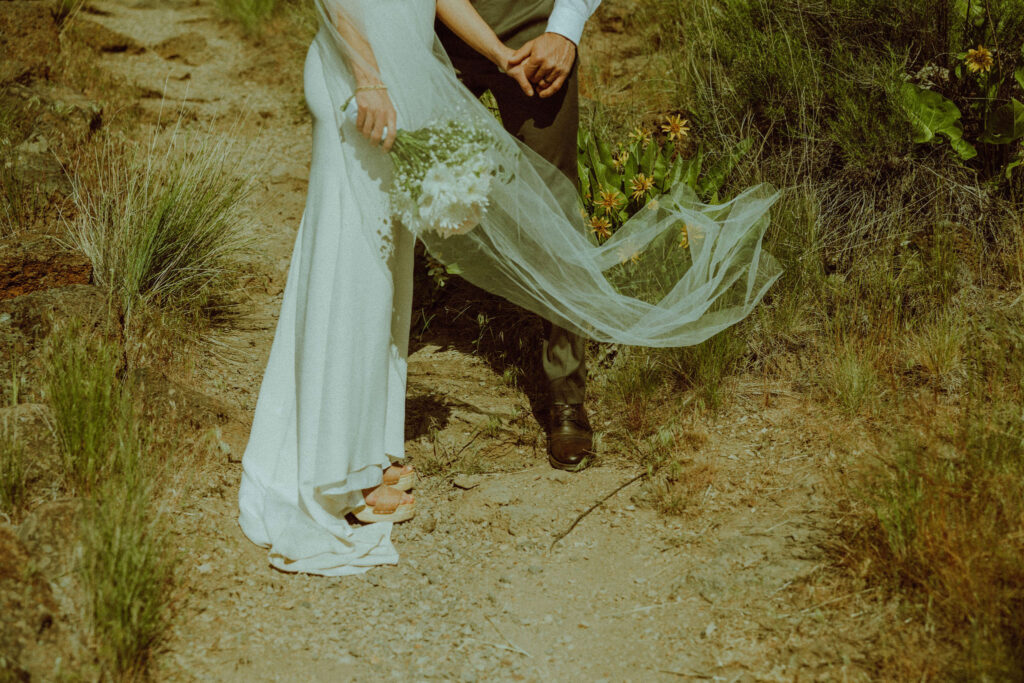 viel blowing in the wind while bride and groom hold hands at smith rock in oregon