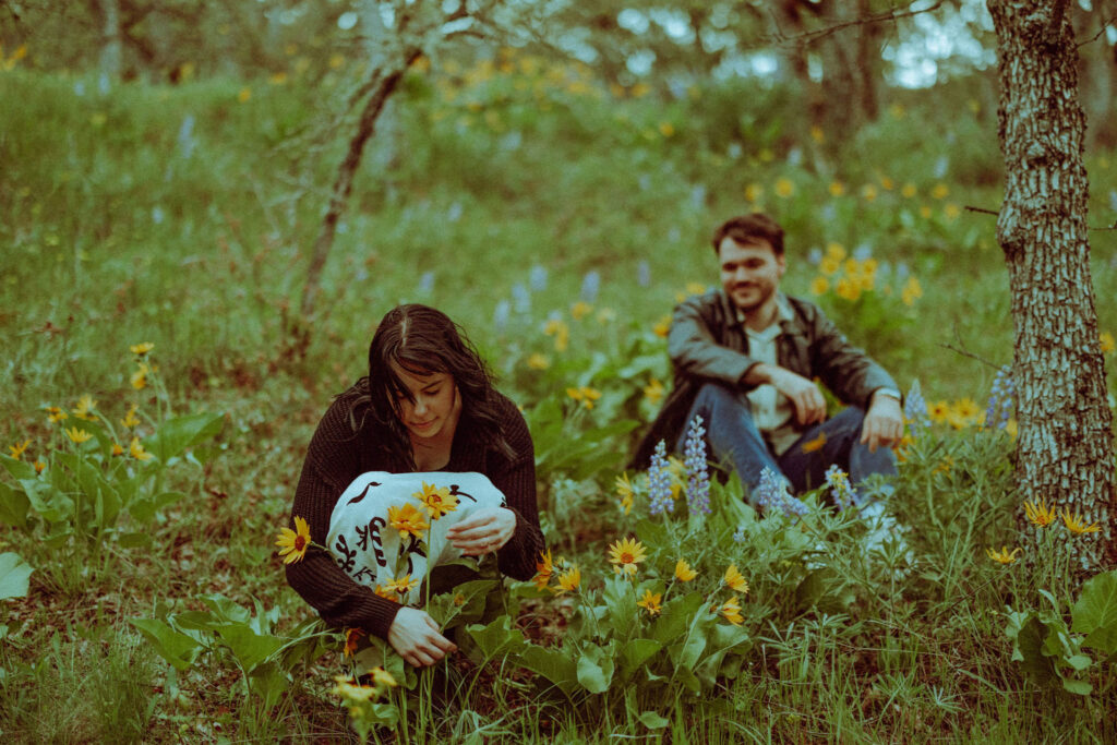 couple picking wildflowers at their oregon engagement session in the gorge