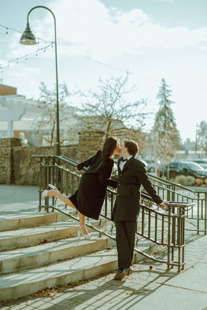 couple kissing on a hand rail for their editorial engagement photos in downtown bend oregon