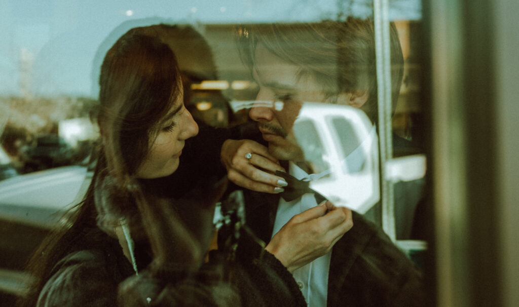  bride and groom facing eachother in a cafe looking through a window