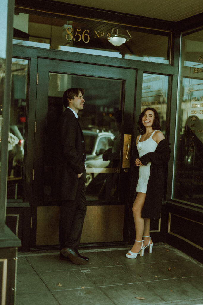 couple posing in front of old store front for their editorial engagement photos in downtown bend oregon