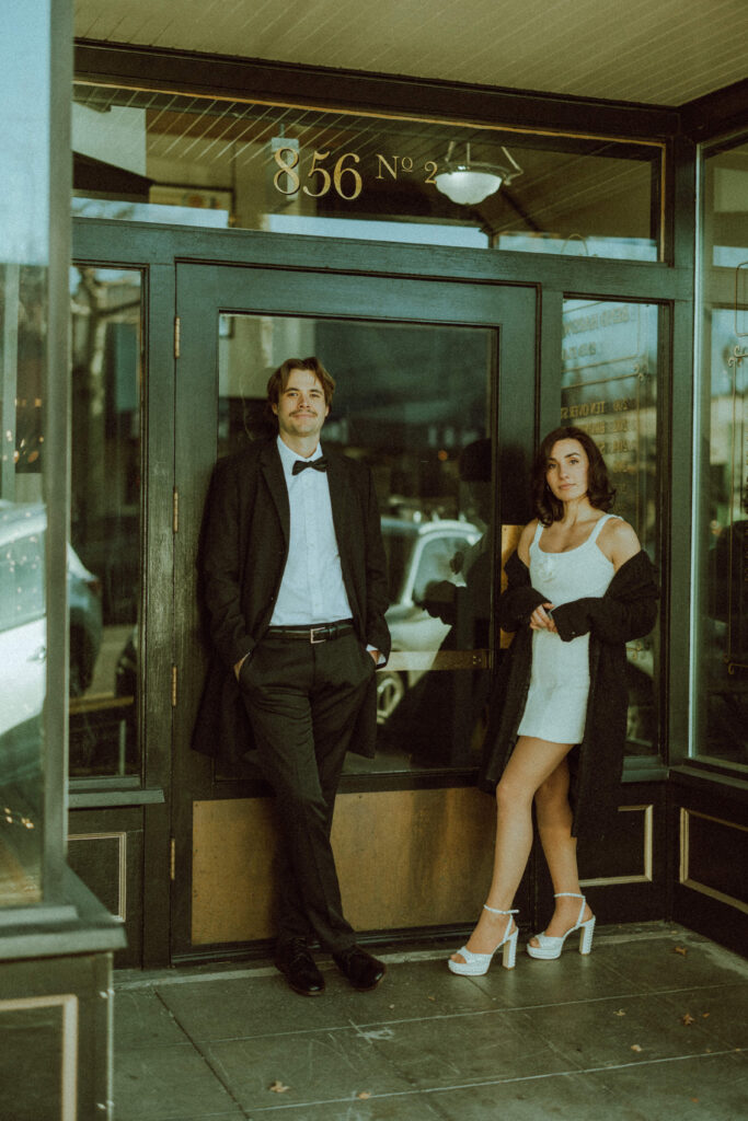 couple posing in front of old store front for their editorial engagement photos in downtown bend oregon