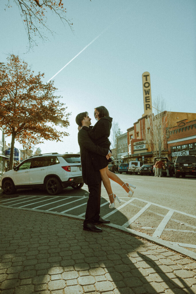 guy picking his fiance in front of tower theater sign in downtown bend oregon