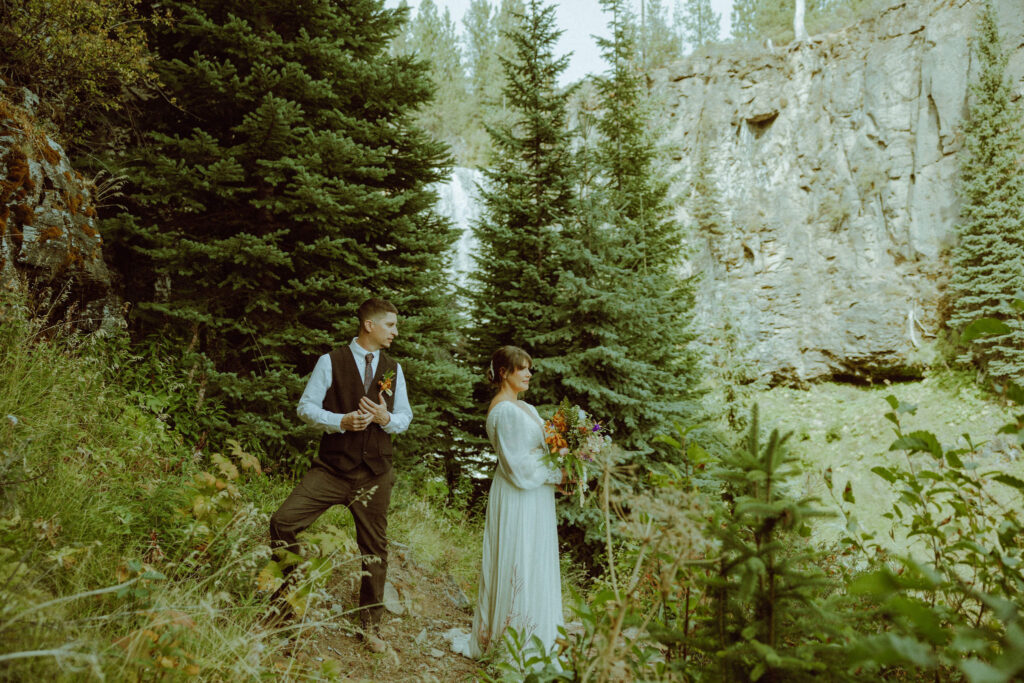 bride and groom pose with tumalo falls in the background on their wedding day 