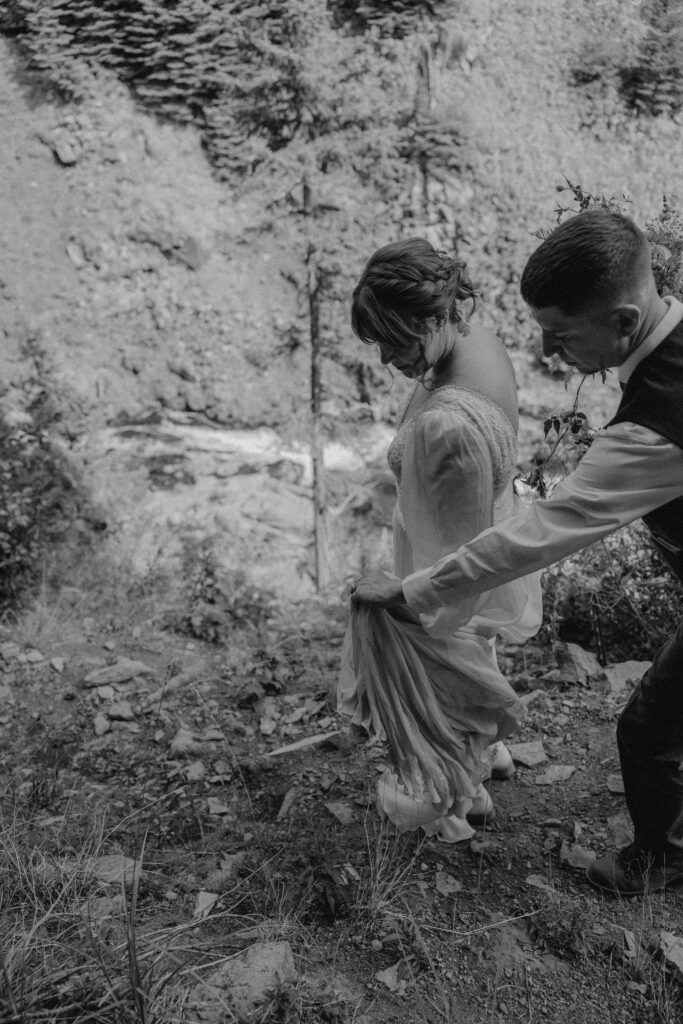 bride and groom pose with tumalo falls in the background on their wedding day 