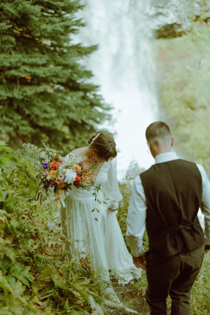 bride and groom pose with tumalo falls in the background on their wedding day 