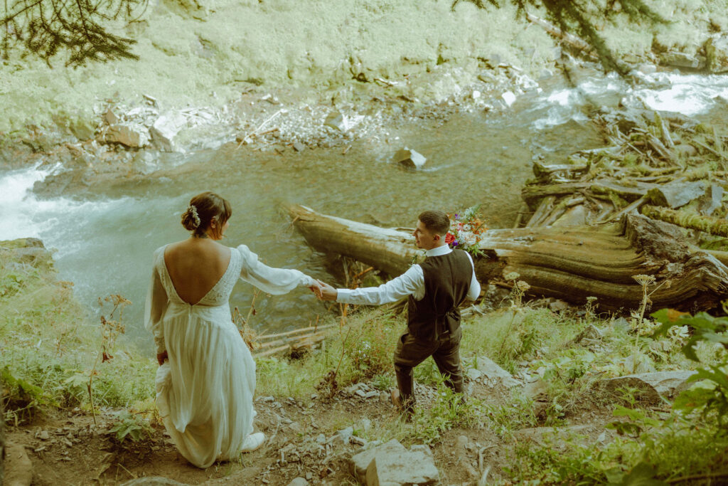 bride and groom pose with tumalo falls in the background on their wedding day 