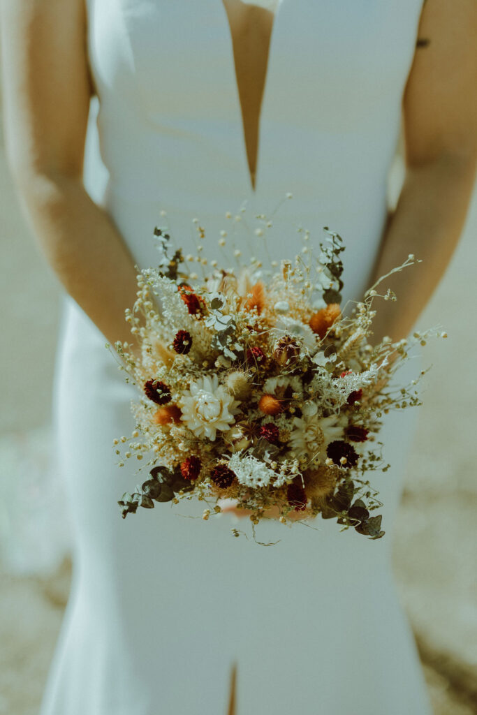 bride holds bouquet of dried florals at eclectic wedding 