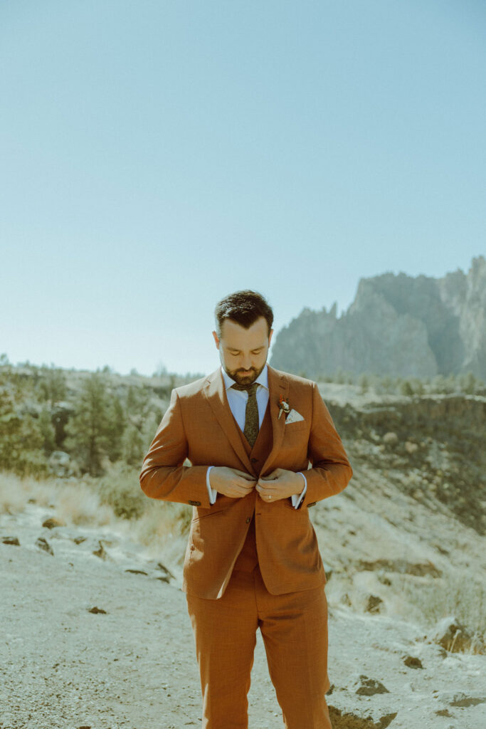 groom buttoning his jacket 