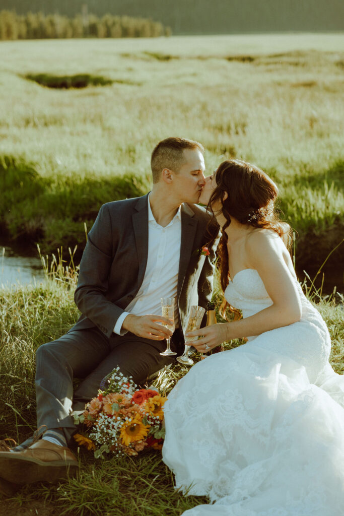  bride and groom sitting on creek bank at sparks lake oregon elopement