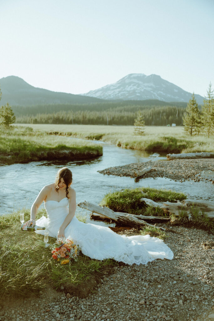  bride sitting on creek bank at sparks lake oregon elopement