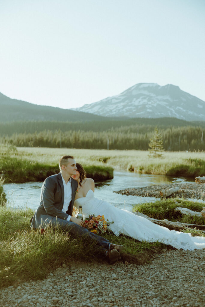  bride and groom sitting on creek bank at sparks lake oregon elopement