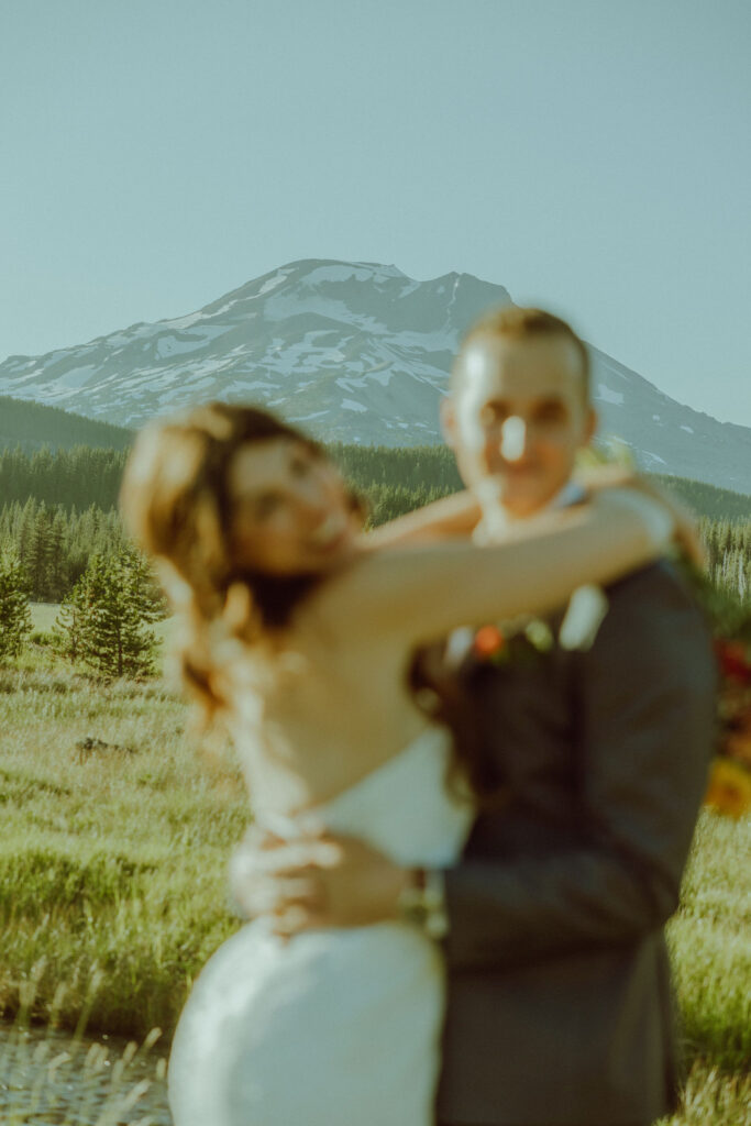 bride and groom embracing in front of south sister mountain in bend oregon at sparks lake meadow elopement location