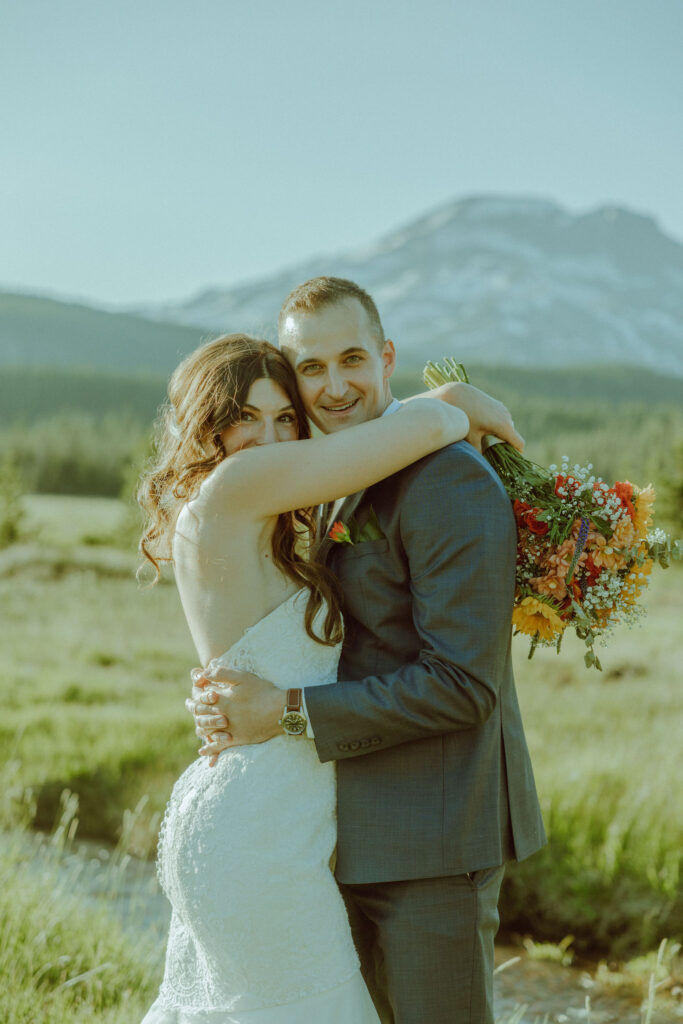 bride and groom embracing in front of south sister mountain in bend oregon at sparks lake meadow elopement location