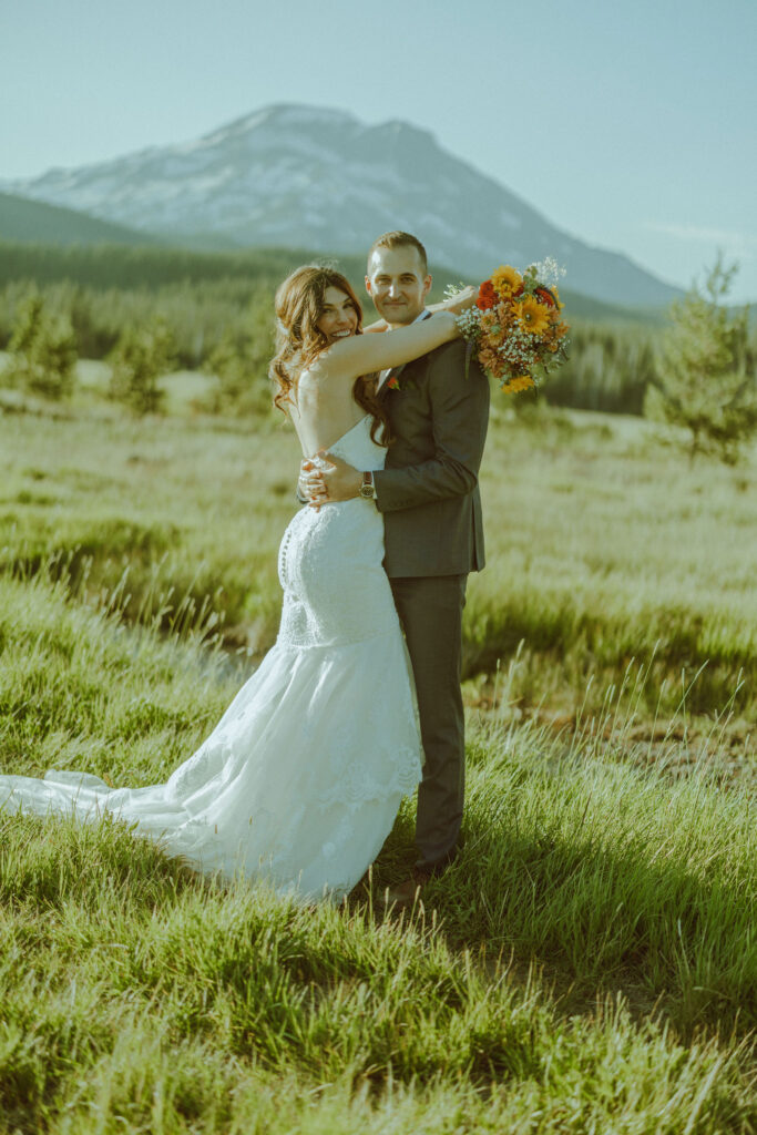 bride and groom embracing in front of south sister mountain in bend oregon at sparks lake meadow elopement location