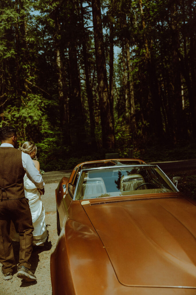 bride and groom at their oregon elopement with a vintage car in a forest