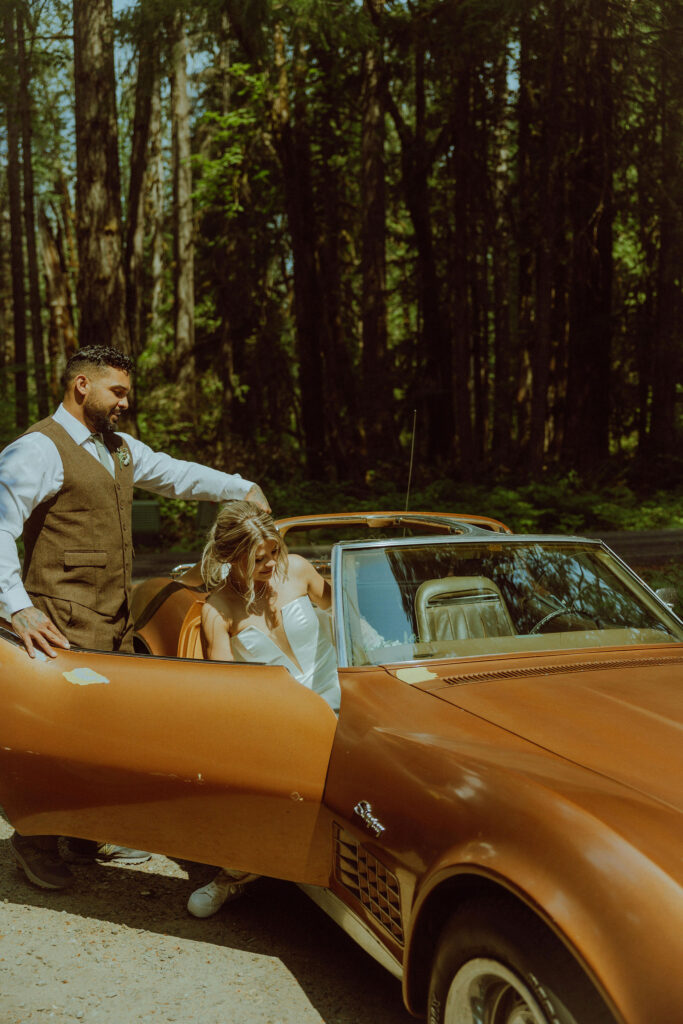 bride and groom at their oregon elopement with a vintage car in a forest