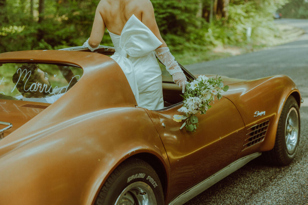 bride and groom at their oregon elopement with a vintage car in a forest