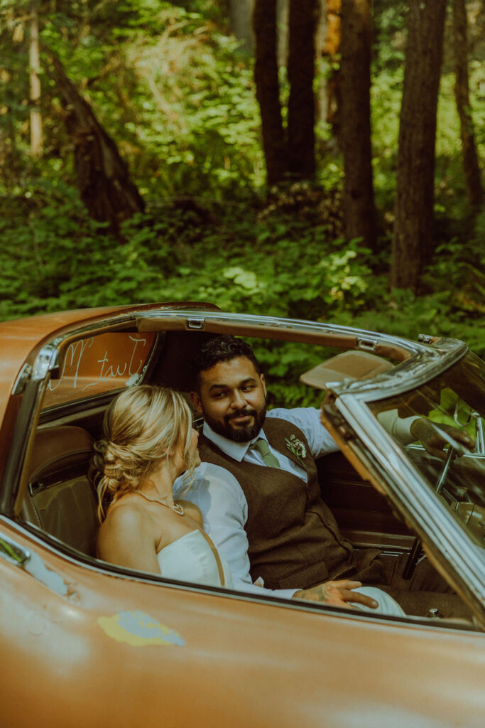 bride and groom at their oregon elopement with a vintage car in a forest