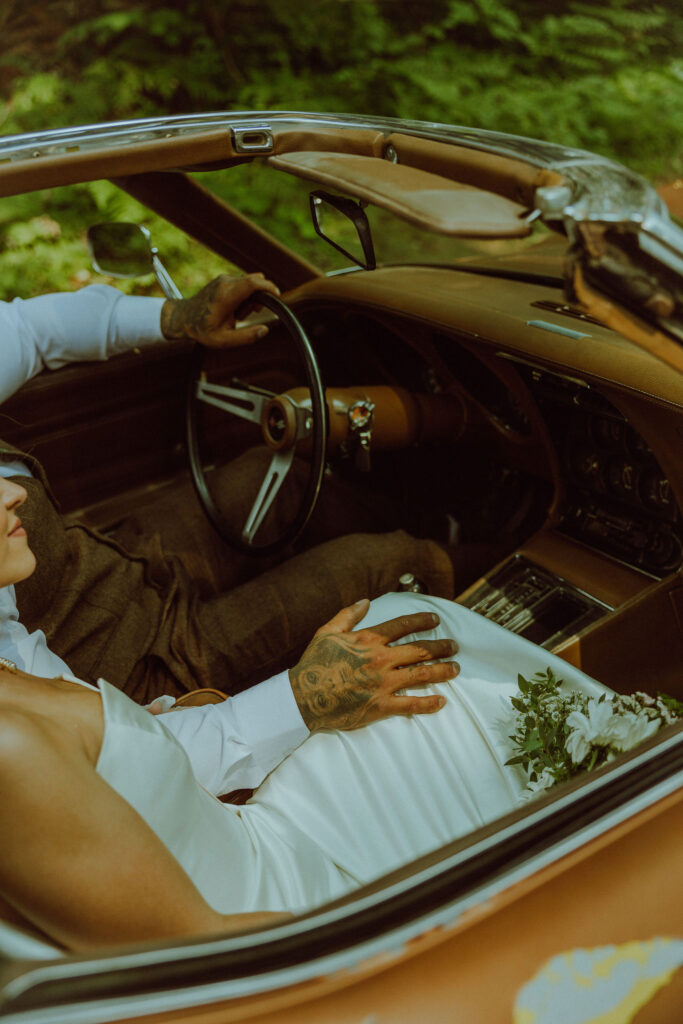 bride and groom at their oregon elopement with a vintage car in a forest