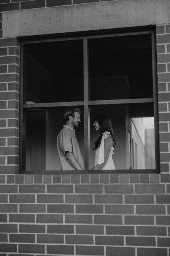 couple standing in window for their engagement photos in bend oregon