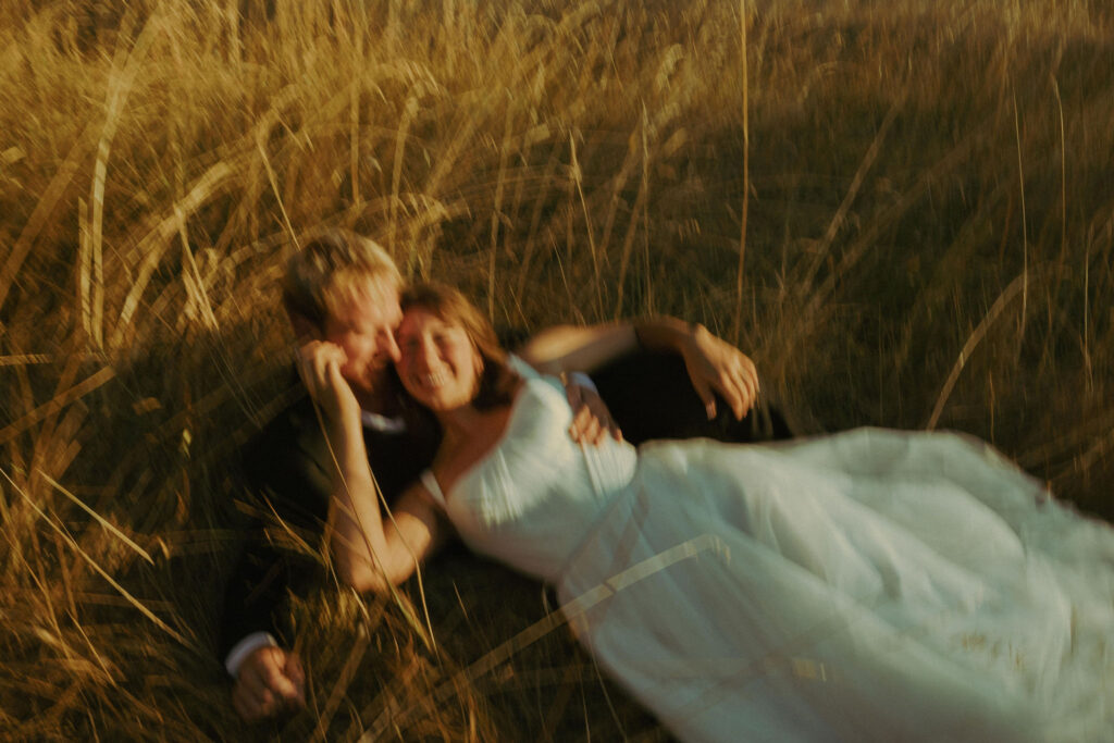 Bride and groom posing laying down in the grass at wedding in Mt Pisgah Arboretum in oregon