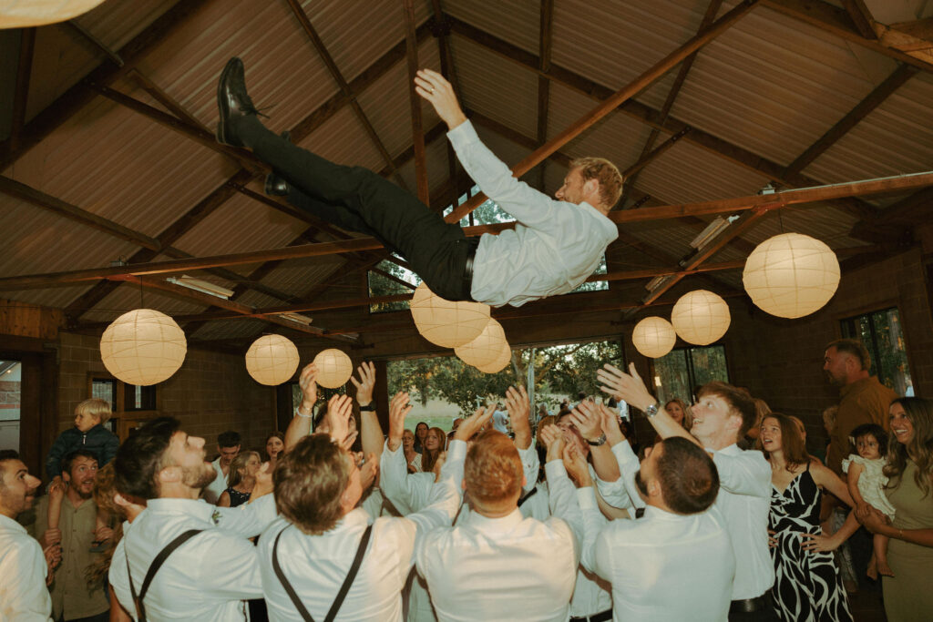 groomsmen throwing groom in the air and catching him at mt pisgah arboretum wedding in oregon 