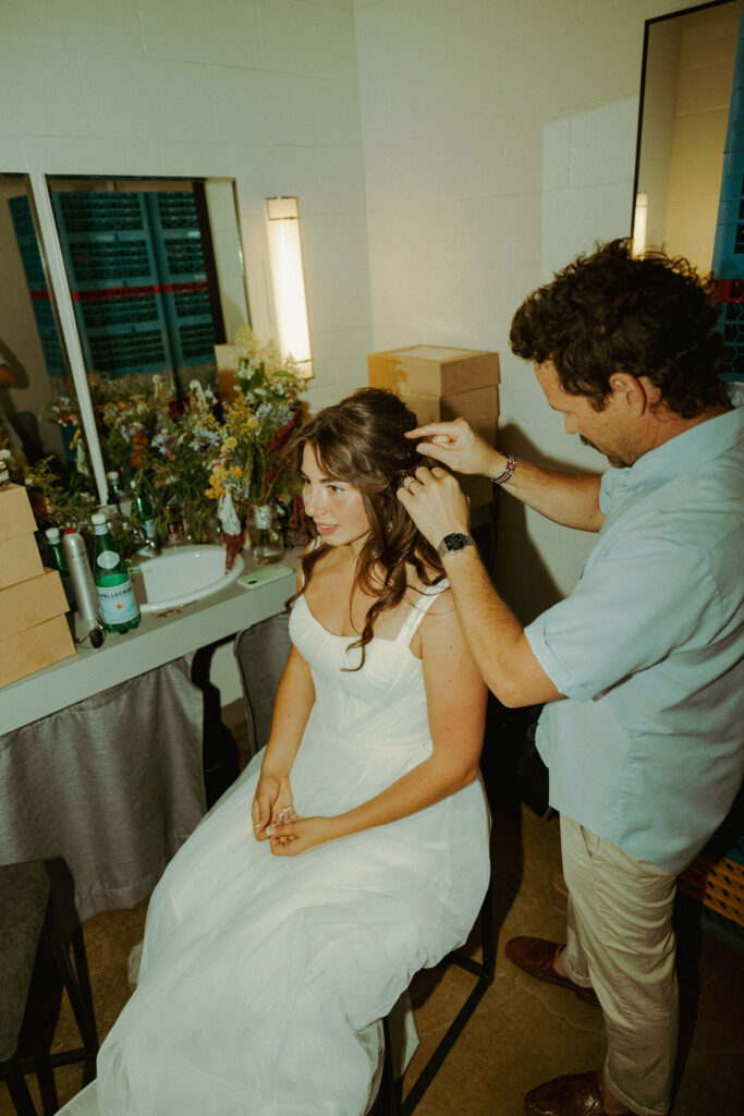 bride getting her hair chopped by hair stylist at wedding reception
