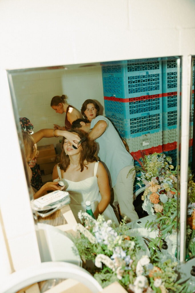 bride getting her hair chopped by hair stylist at wedding reception
